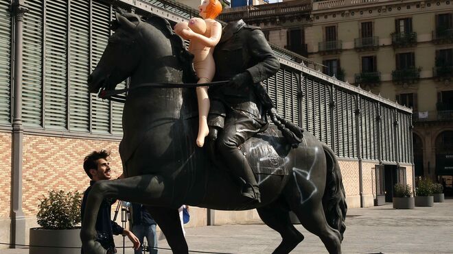 Un artista coloca una muñeca hinchable como protesta en la estatua ecuestre del general Franco frente al edifico del Born de Barcelona. Hoy por segundo día siguen las acciones de protesta contra esta exposición.