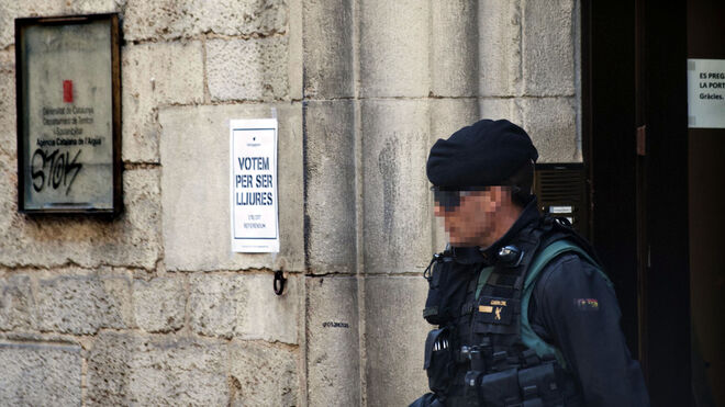 Un agente de la Guardia Civil en Girona junto a un cartel que anima a votar el 1-O.