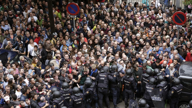 Agentes antidisturbios de la Policía Nacional forman un cordón de seguridad en los alrededores del colegio Ramón Llull de Barcelona