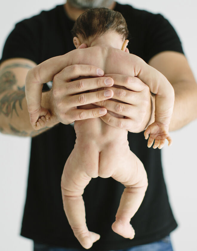 Muñeco de silicona representando a un recién nacido que es sujetado por un adulto