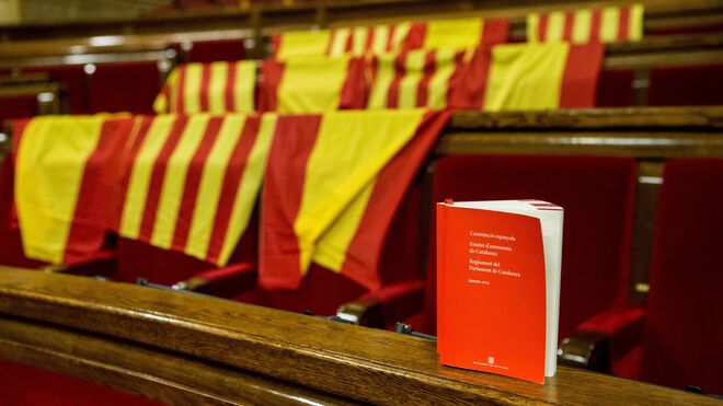 El Parlament, con banderas de España y de Cataluña y un ejemplar con la Constitución Española.