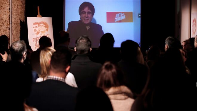 El expresidente de la Generalitat, Carles Puigdemont, conversa por videoconferencia con candidatos y simpatizantes durante la inauguración de la sede de campaña de Junts per Catalunya