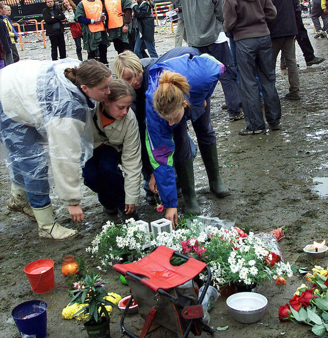 Unas jóvenes ponen flores en el recinto del festival musical de Roskilde, el sábado 1 de julio de 2000, tras el incidente fatal ocurrido aquí ese año