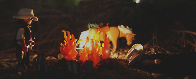 Un par de Playmobil buscadores de oro acampan de noche frente a una hoguera