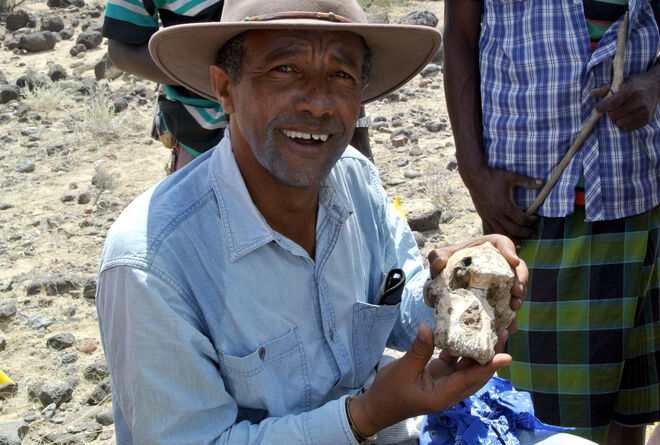 El investigador Yohannes Haile-Selassie posa con el cráneo en el yacimiento