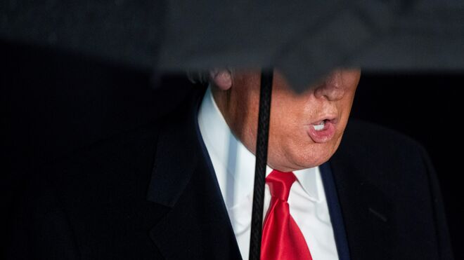 Donald Trump oculto bajo su paraguas