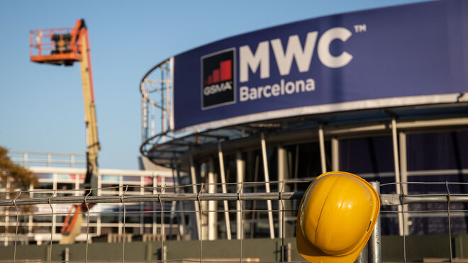 Un casco de obra amarillo colgado en una de las vallas que cierran el recinto del Mobile World Congress (MWC) durante el desmantelamiento de los stands.