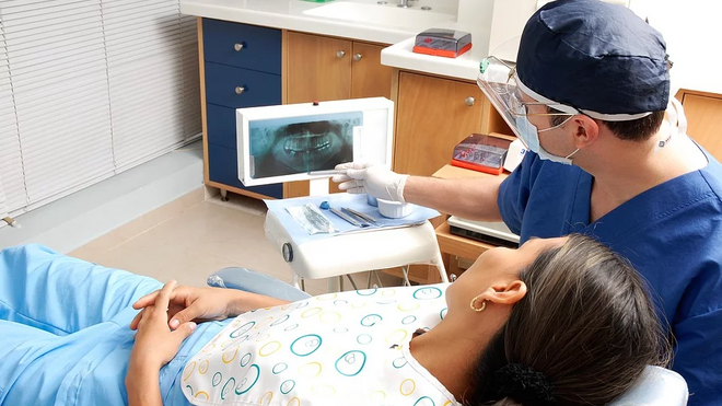 Un dentista atiende a una usuaria en una consulta odontológica.