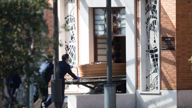 Dos trabajadores introducen un ataúd por la puerta de la funeraria municipal de Madrid