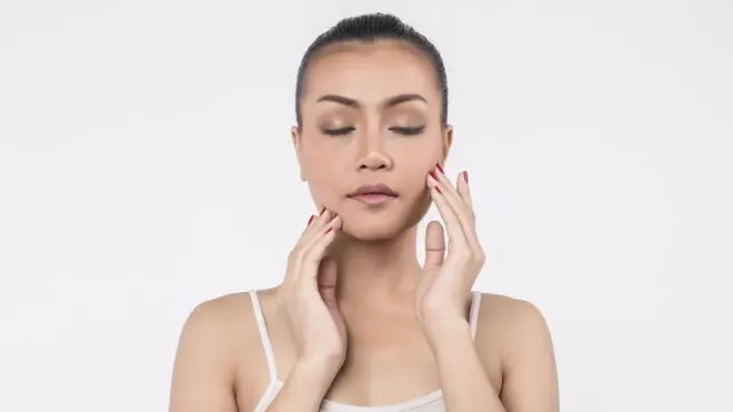 Mujer realizándose un masaje facial con las manos