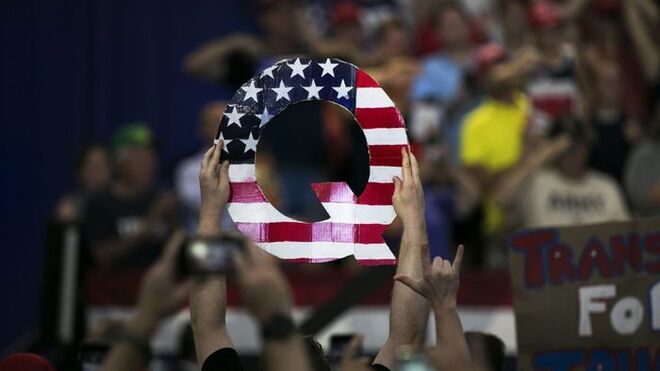 Asistentes a la Convención Republicana sostienen un logo de QAnon