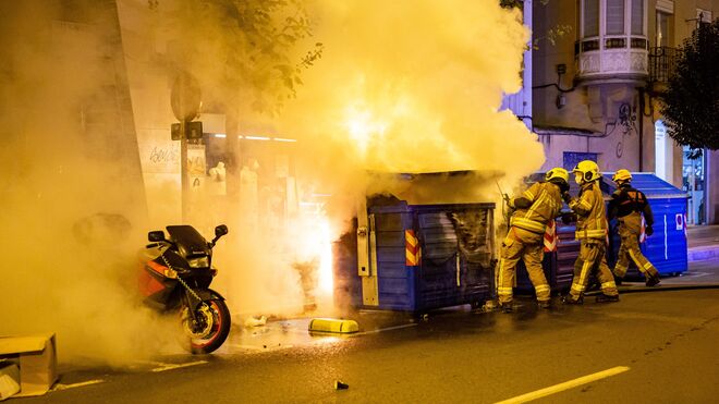Bomberos sofocan las llamas del contenedor de papel que arde durante los disturbios registrados en Logroño