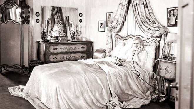 La estrella de Hollywood Jean Harlow (1911 - 1937) en su dormitorio, llamando por teléfono desde su cama, en 1932.