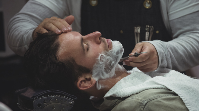 Barbero perfilando la barba de un cliente