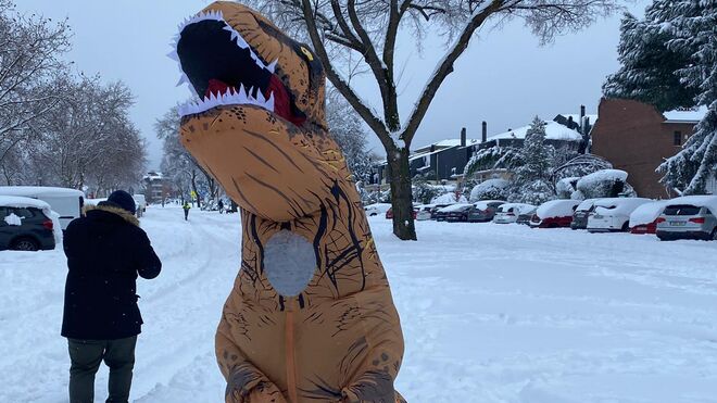 Un vecino en medio de la nieve disfrazado de dinosaurio