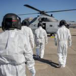 Varios militares totalmente protegidos se preparan para subir a un helicóptero.