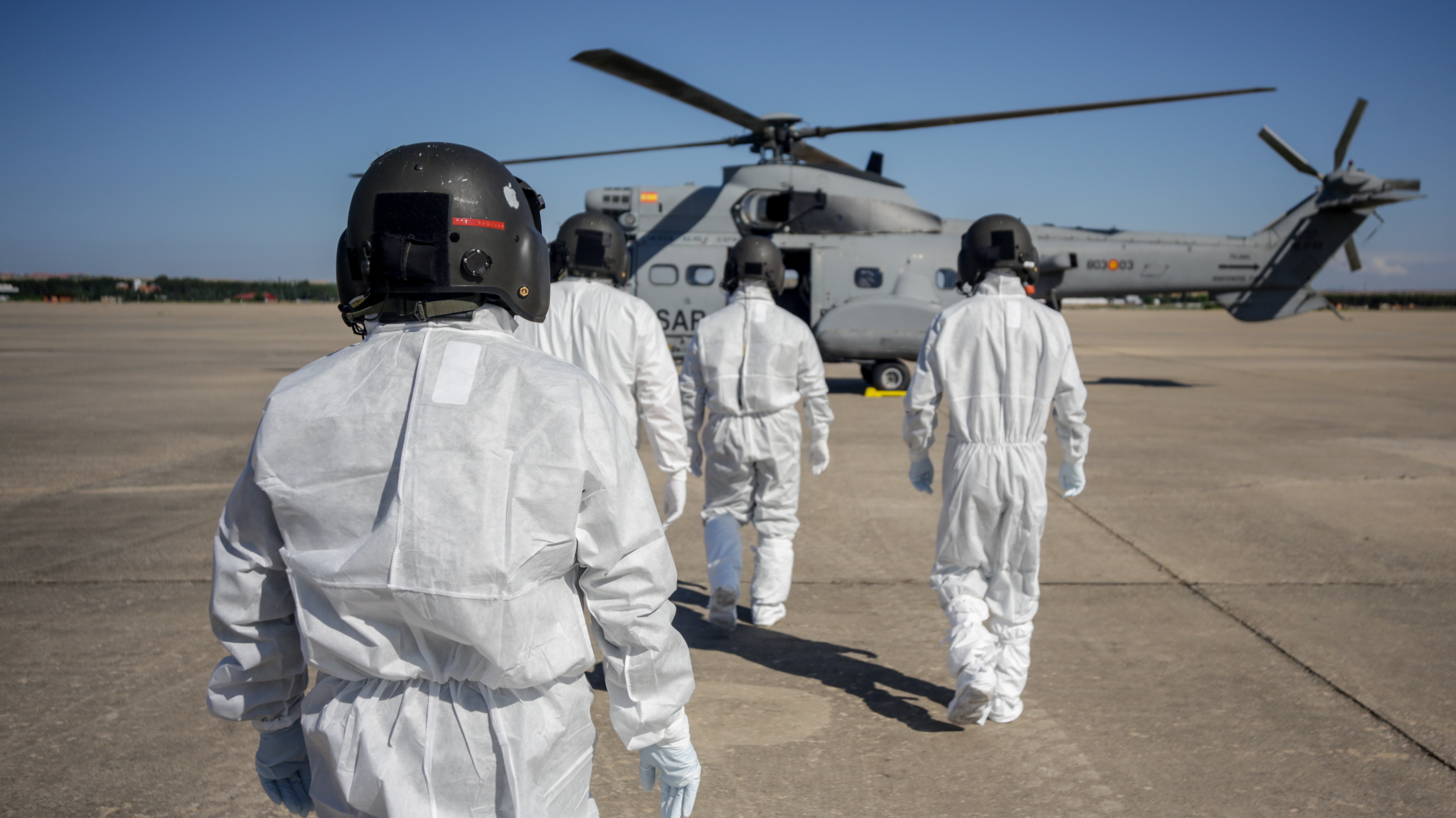 Varios militares totalmente protegidos se preparan para subir a un helicóptero.