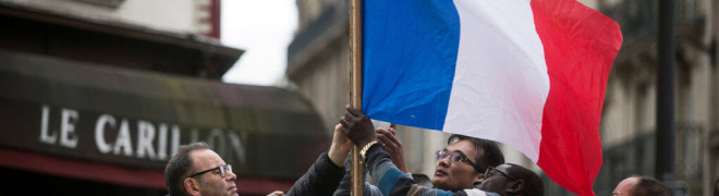 Tres personas colocan una bandera francesa en una foto de archivo.