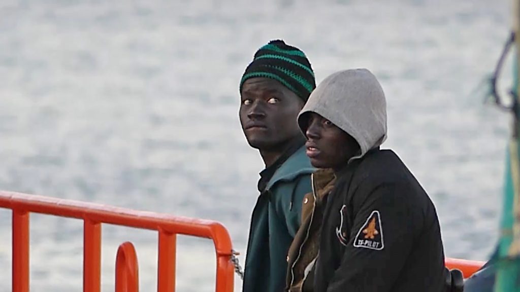 Dos jóvenes migrantes bajan de un barco de la Cruz Roja en el puerto de Arguineguín (Gran Canaria, España).