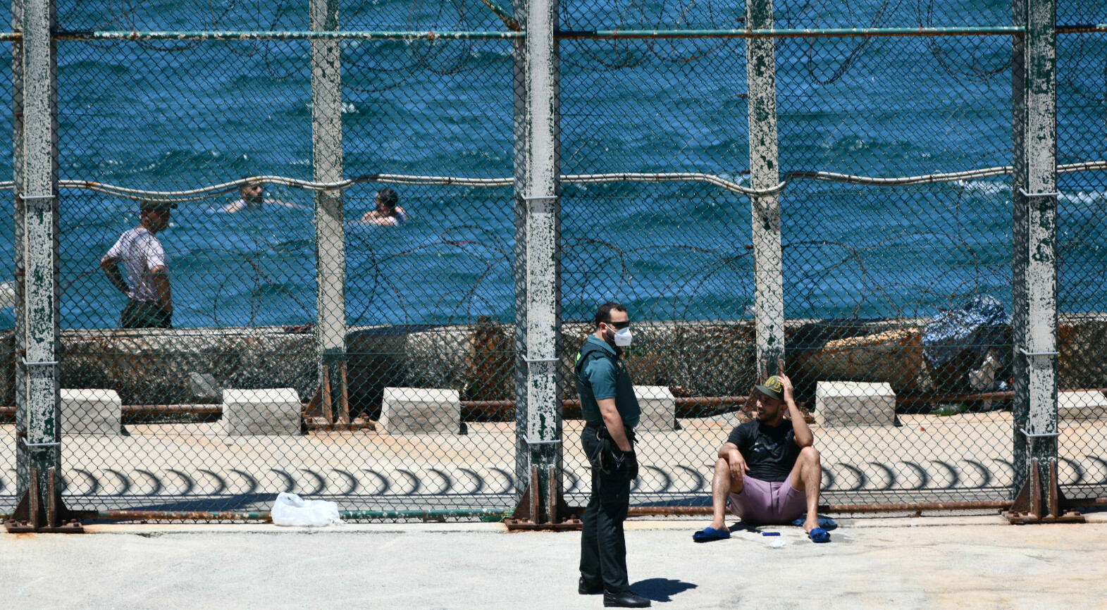 Un agente de Guardia Civil con un joven migrante marroquí en las inmediaciones de la valla de Ceuta, en la playa del Benzú