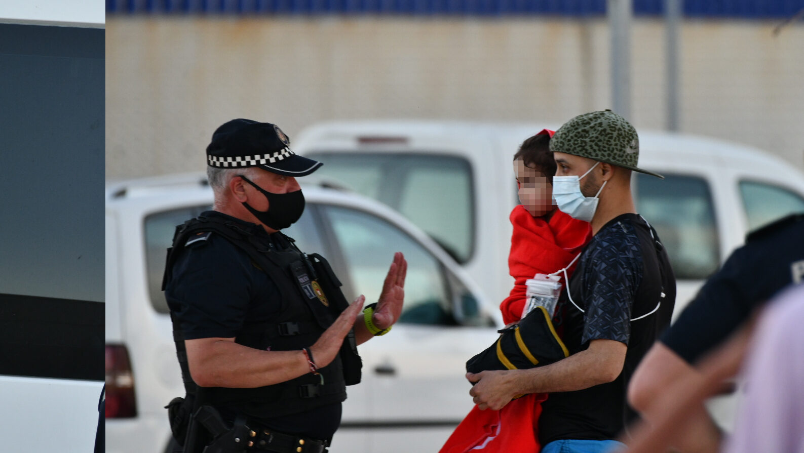 Un policía junto a un hombre con una niña en la playa del Tarajal, junto a Marruecos.