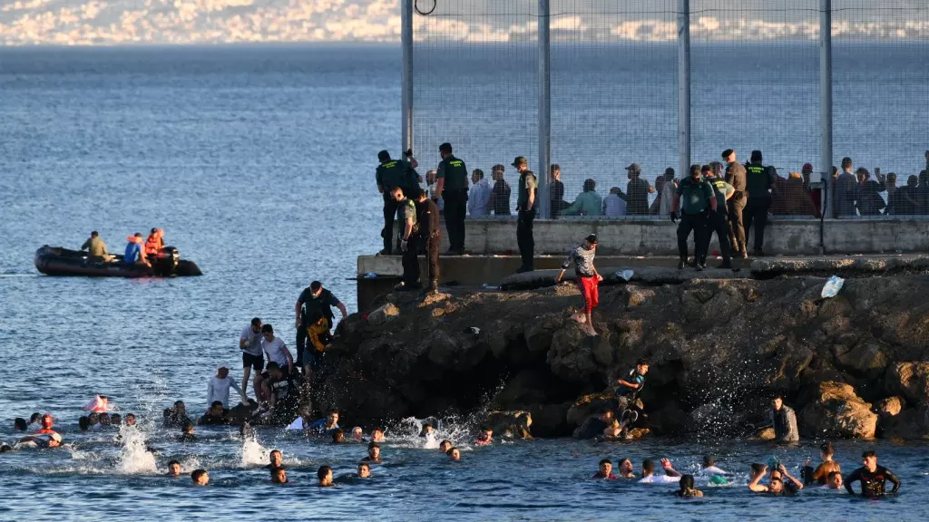 Inmigrantes marroquíes bordean el espigón del Tarajal para entrar en Ceuta.