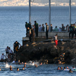 Inmigrantes marroquíes bordean el espigón del Tarajal para entrar en Ceuta.