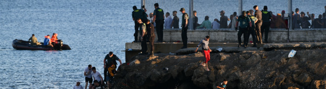 Inmigrantes marroquíes bordean el espigón del Tarajal para entrar en Ceuta.
