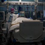 Trabajadores sanitarios protegidos atienden a un paciente en la UCI