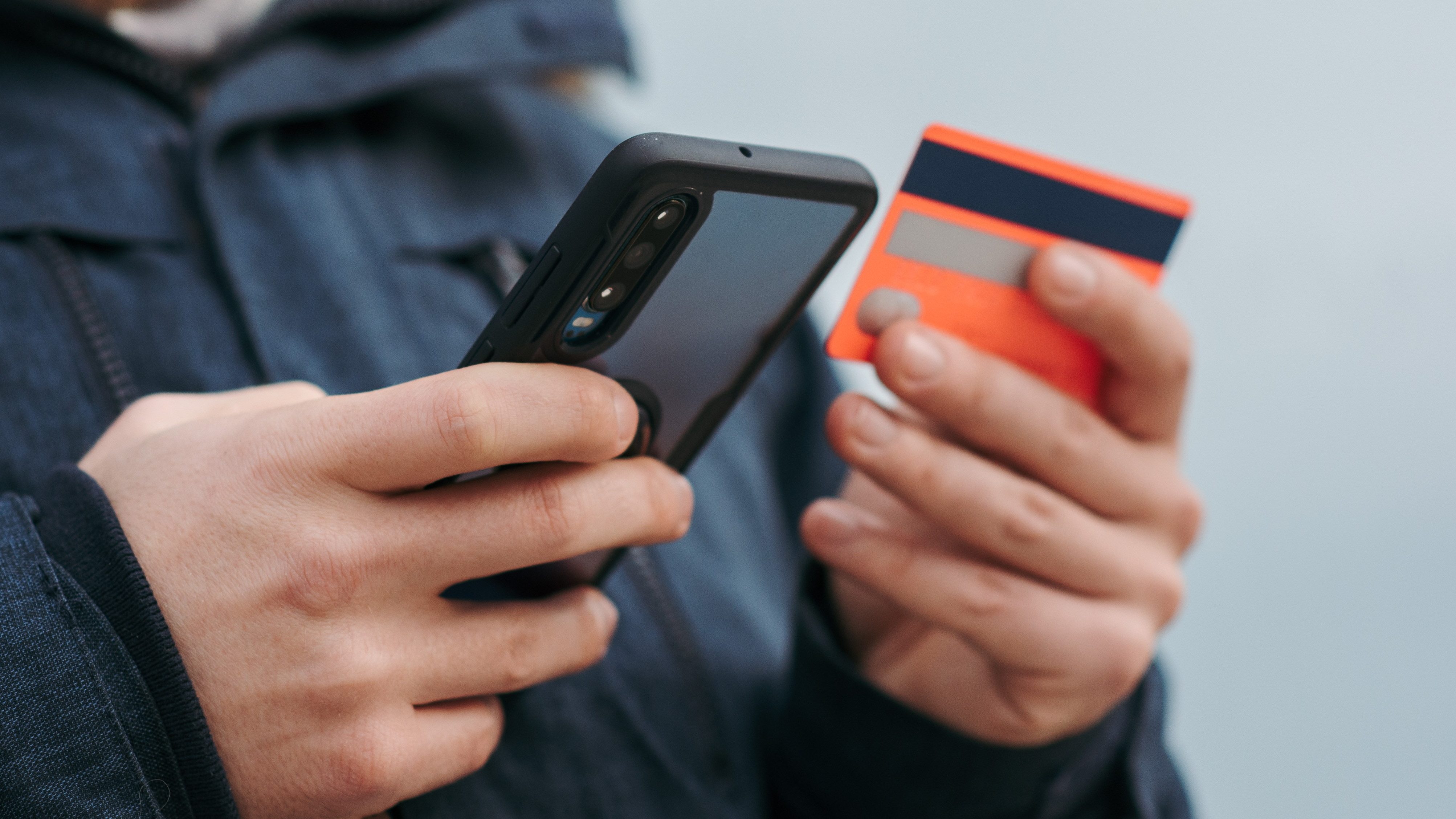Un usuario con su tarjeta de crédito y el móvil reservando un vuelo.