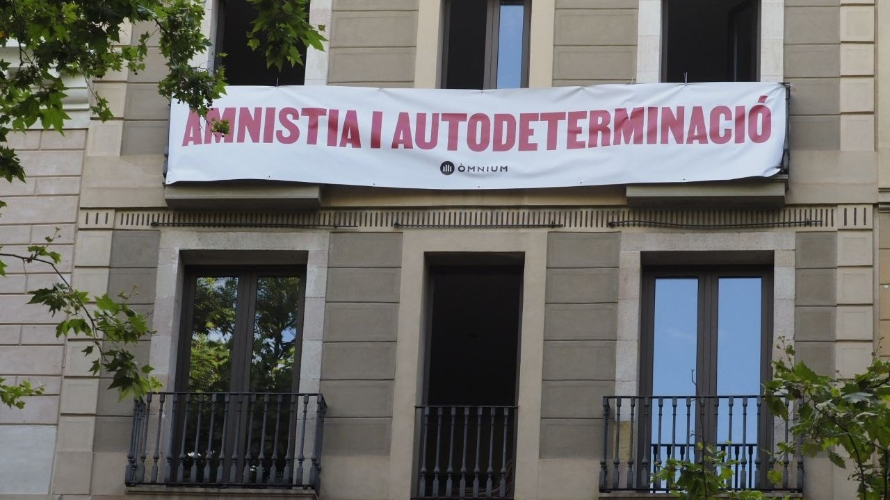 Òmnium despliega una pancarta ante el Liceo para reclamar a Pedro Sánchez amnistía y autodeterminación