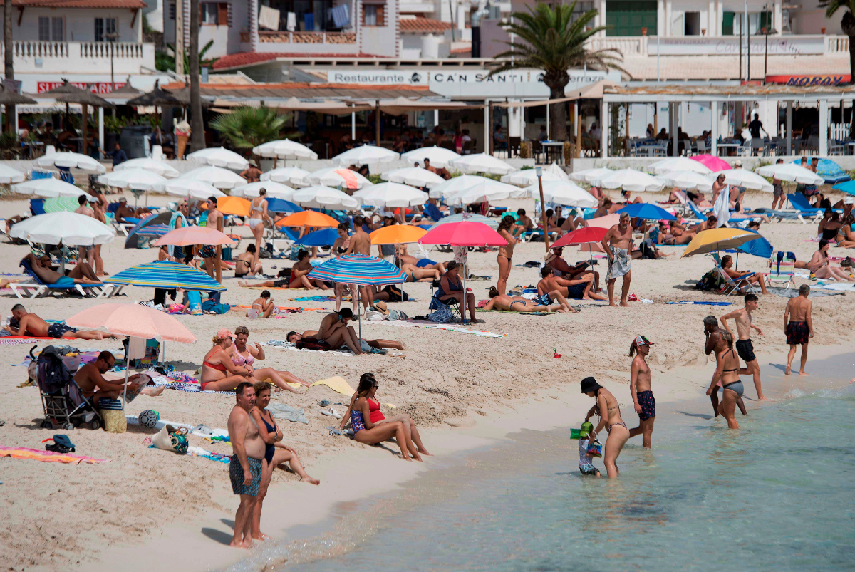Varios bañistas disfrutan de una soleada jornada en la playa de Punta Prima de Menorca.