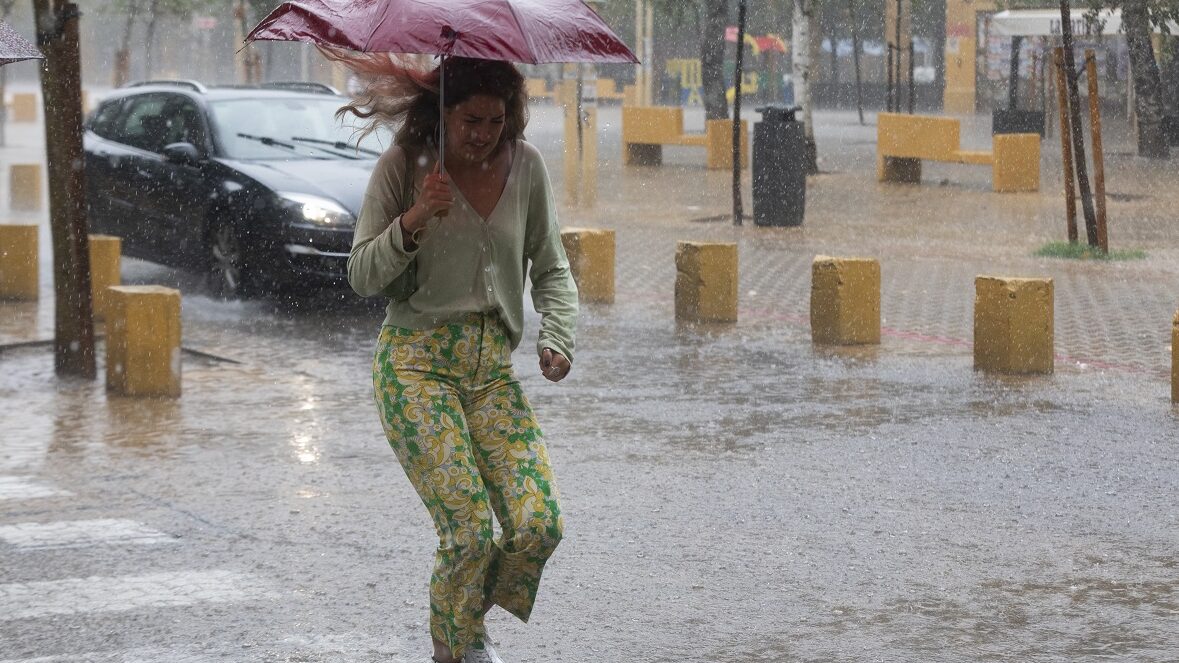 Una mujer cruza un charco durante una tormenta en Sevilla
