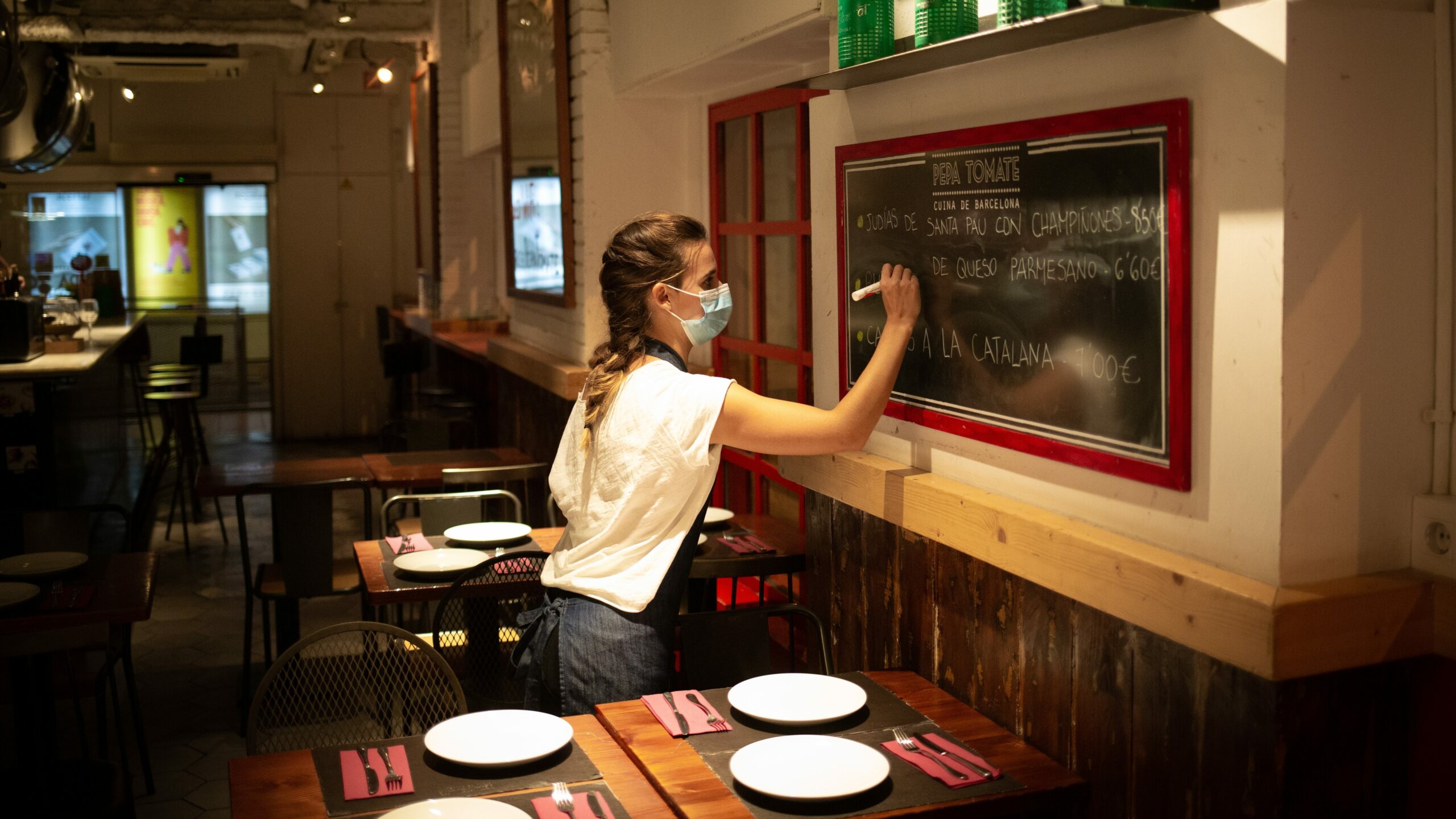 Una camarera apunta platos en una pizarra en el interior de un bar de Barcelona. Europa Press