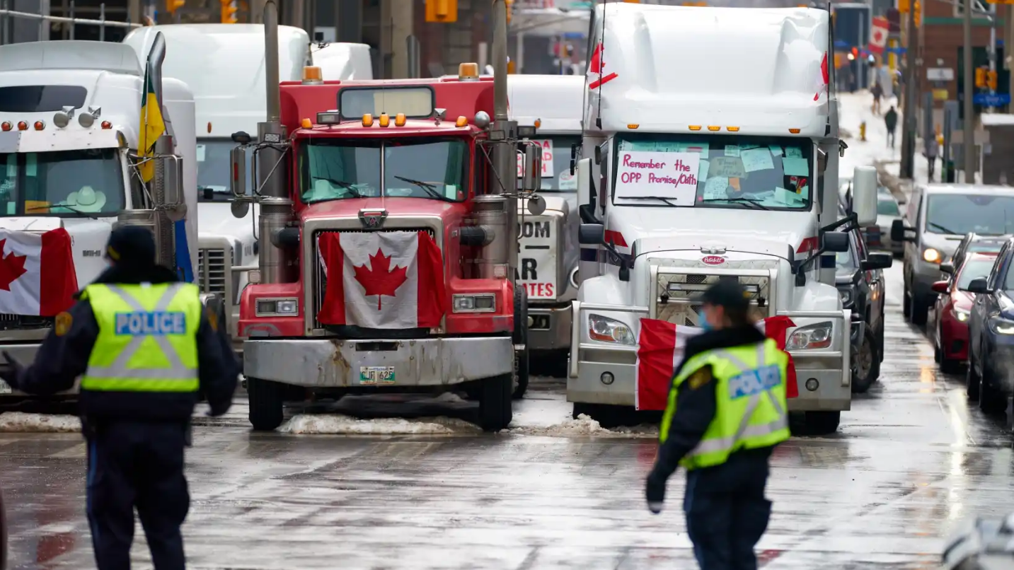 Dos policías de Ottawa frente a camiones de manifestantes antivacunas.