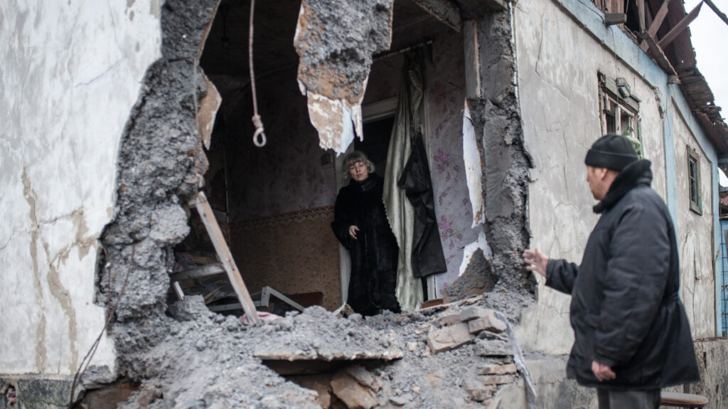 Una mujer observa su casa derruida en Donbas (Ucrania)