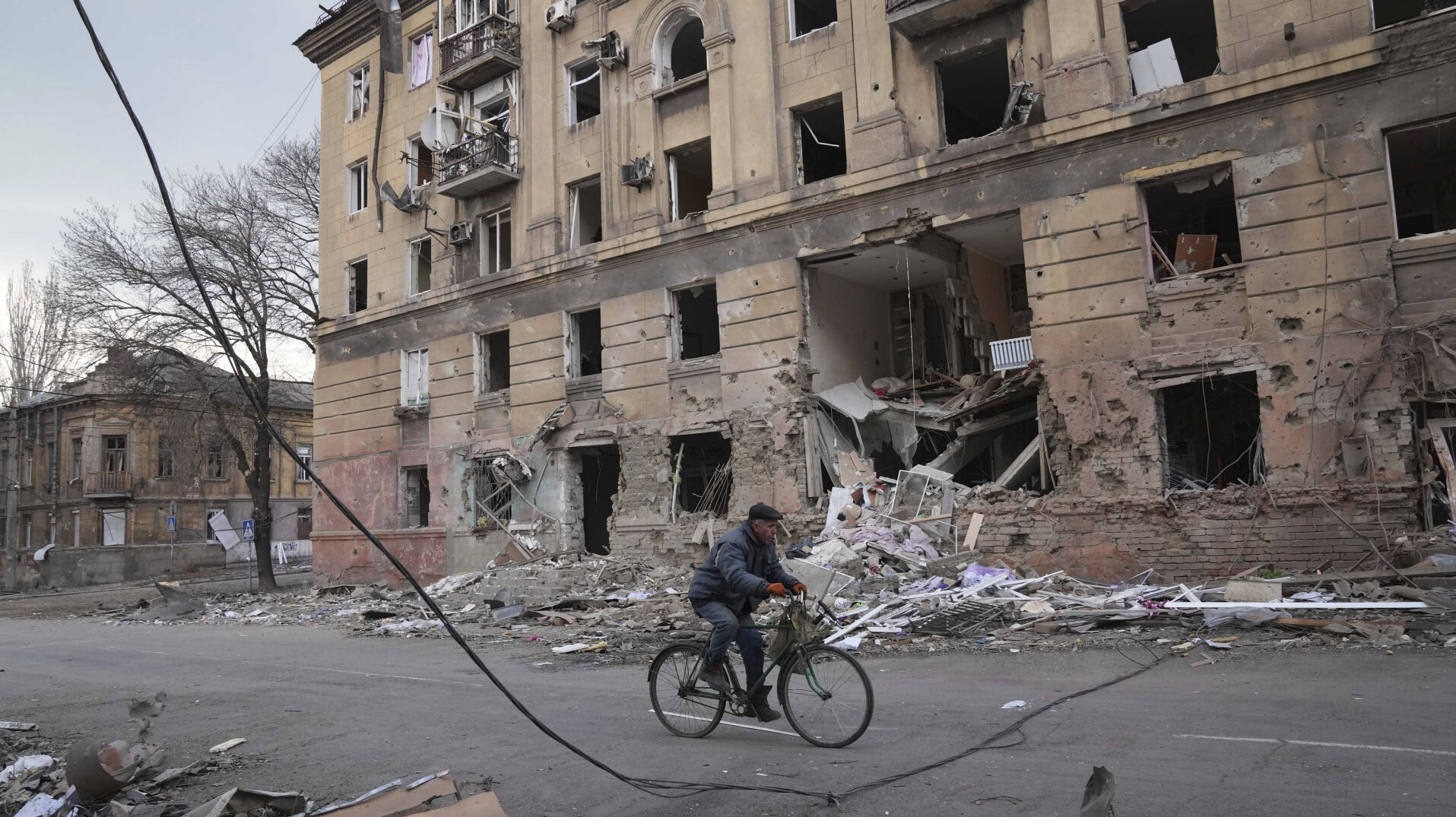 Un hombre en bicicleta frente a un edificio bombardeado en Mariúpol (Ucrania)