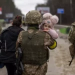 Un soldado ucraniano sostiene a un bebé para cruzar el río de Irpin (Kyiv, Ukraine) (Gtres/ AP Photo/Emilio Morenatti)