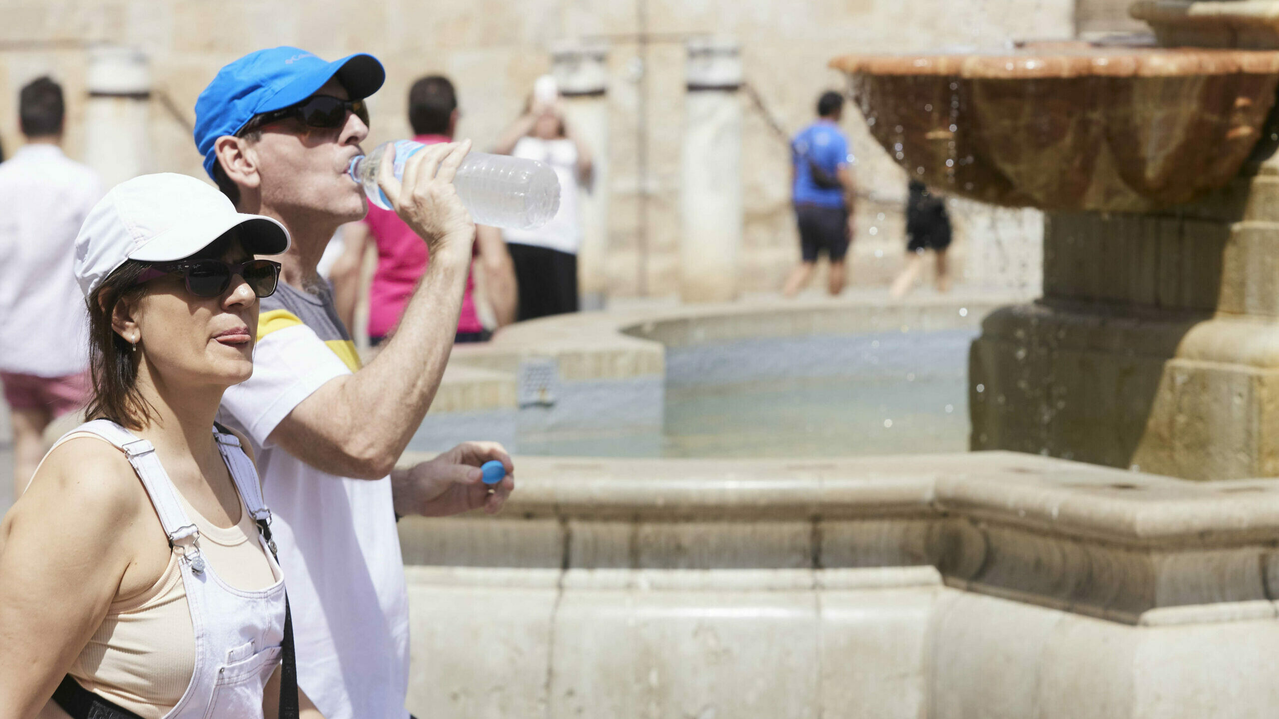 Un señor bebe agua para combatir el calor