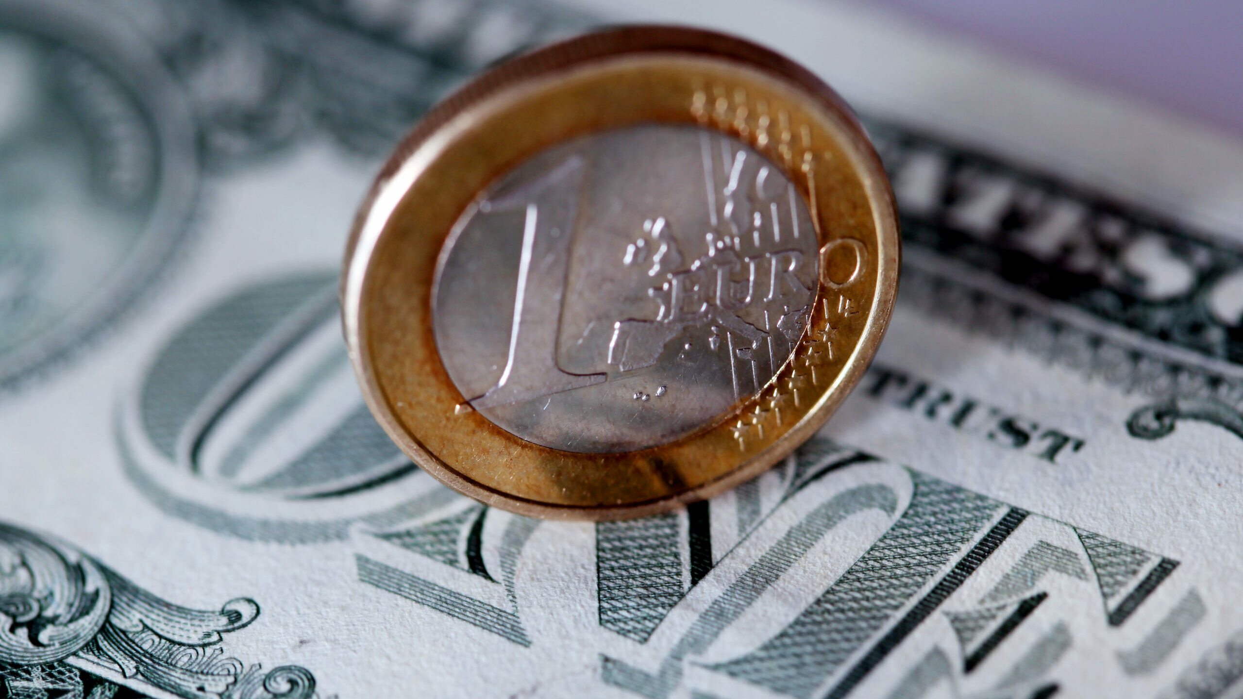 Una moneda de un euro y un billete de un dólar