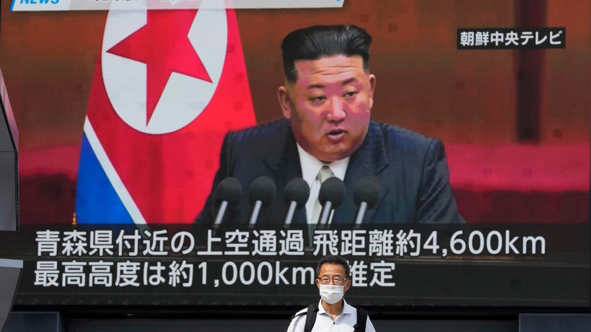 Una persona camina bajo una pantalla gigante que muestra noticias sobre el lanzamiento de un misil de Corea del Norte, con una imagen del líder norcoreano Kim Jong-un