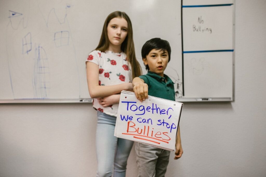 Dos menores con un cartel contra el acoso escolar
