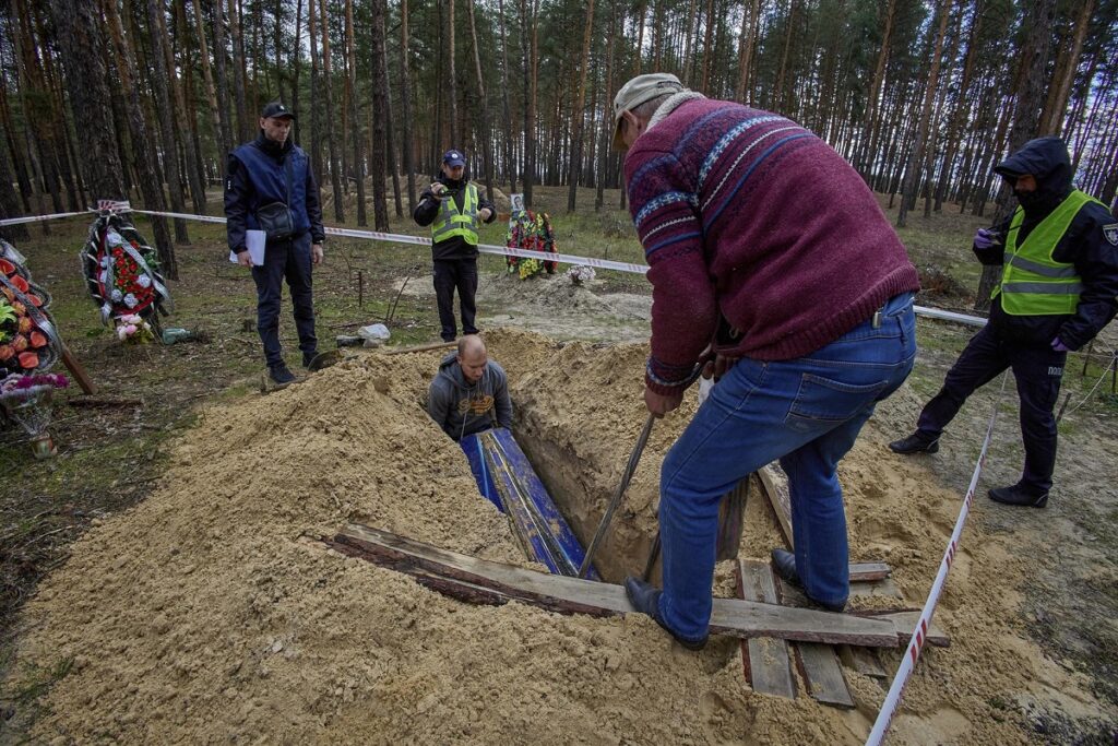 Forenses ucranianos durante la exhumación de un cadáver en una fosa común en Izium, Járkov.