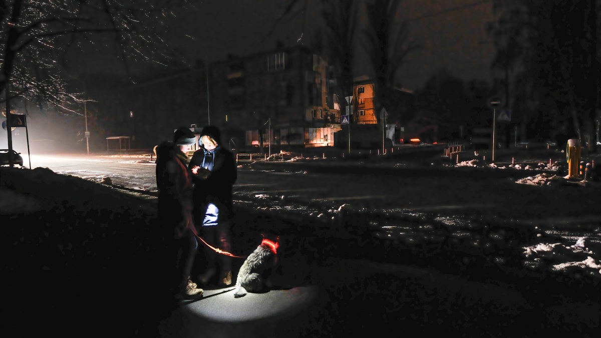Dos personas se alumbran con un teléfono móvil en una calle oscura de Kiev (Ucrania)