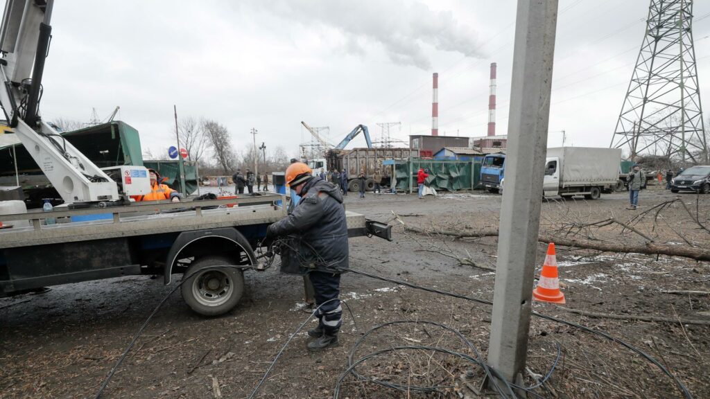 Los trabajadores comunales reparan la línea eléctrica después de un ataque con misiles en Kiev