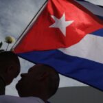 Padre e hijo junto a la bandera de Cuba