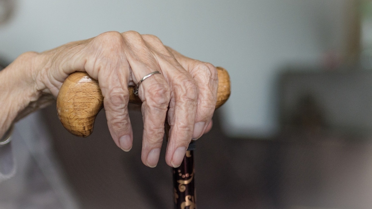 La mano de una anciana con bastón