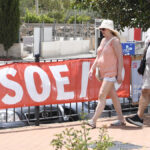 Unas personas caminan junto a una pancarta del PSOE de Mojácar (Almería)