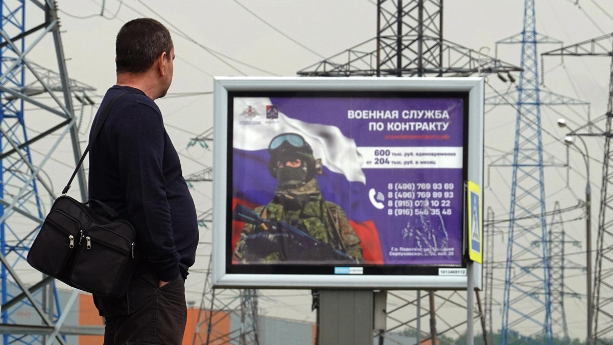 Un hombre se para frente a una valla publicitaria en apoyo de las fuerzas armadas rusas leyendo el servicio de contrato, en las afueras de Moscú, Rusia.