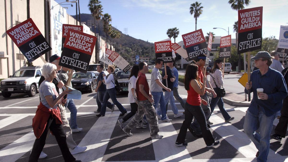 Miembros de la asociación de guionistas de cine y televisión, "Writers Guild of America", sostienen carteles de protesta por la huelga de guionistas de Hollywood
